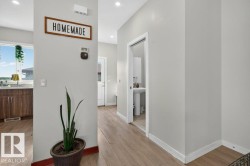Open-concept space featuring wood-finish flooring, recessed lighting, a kitchen with rich wood-finish cabinetry, and a window with natural light - 