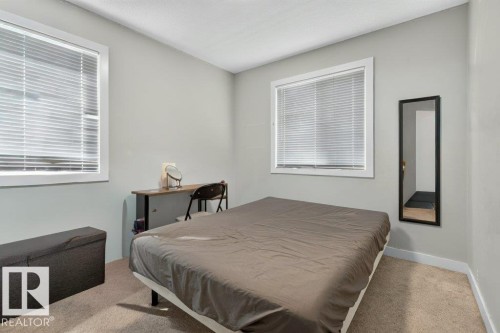 Neutral-toned room featuring two windows with white blinds, light gray walls, and carpet flooring - 43 Sienna Boulevard, Fort Saskatchewan, AB - Indoor Photo Showing Bedroom