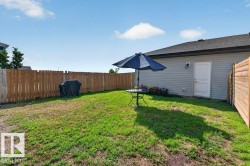 Expansive backyard featuring a manicured lawn, full perimeter wood fencing, and a side exterior door - 
