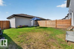 Expansive backyard with a manicured lawn, featuring a horizontal plank wood fence, a detached garage with siding, and a flower bed - 