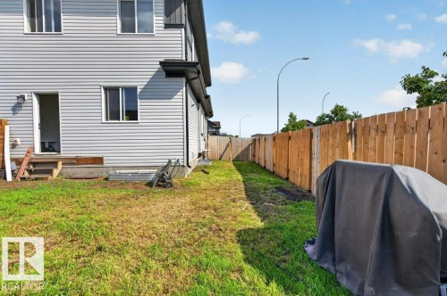 Backyard area featuring a wooden privacy fence and a rear entrance with a small wooden deck - 43 Sienna Boulevard, Fort Saskatchewan, AB - Outdoor