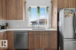 Kitchen featuring wood-finish cabinetry, light grey tile backsplash, white countertops, and a stainless steel dishwasher - 