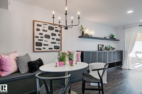 Dining area featuring a built-in bench, wood-finish flooring, a contemporary chandelier, and a built-in credenza with shelving - 19F Meadowlark Village Nw, Edmonton, AB - Indoor Photo Showing Dining Room