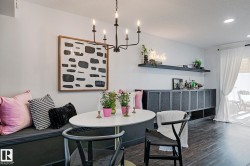 Dining area featuring a built-in bench, wood-finish flooring, a contemporary chandelier, and a built-in credenza with shelving - 