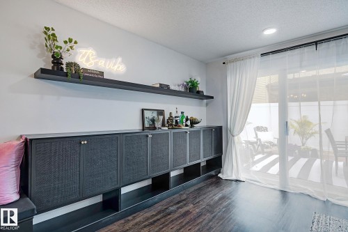 Built-in cabinetry with textured panel doors, integrated open shelving, and a floating wall shelf - 19F Meadowlark Village Nw, Edmonton, AB - Indoor Photo Showing Other Room