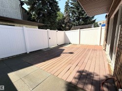 Patio area featuring an expansive wood-finish deck with a white panel fence and gate - 