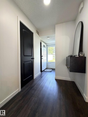 Dark wood-finish flooring extending through the entry hall - 19F Meadowlark Village Nw, Edmonton, AB - Indoor Photo Showing Other Room