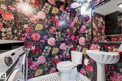 Compact utility room featuring a pedestal sink, white toilet, and black and white hexagonal floor tiles - 
