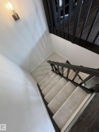 Carpeted staircase with dark wood-finish handrails and balusters - 