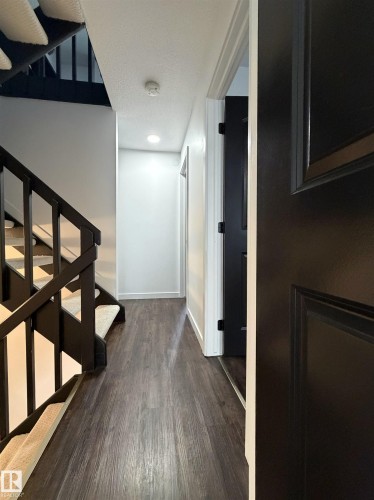 Hallway featuring wood-finish flooring, recessed lighting, and a paneled door - 19F Meadowlark Village Nw, Edmonton, AB - Indoor Photo Showing Other Room