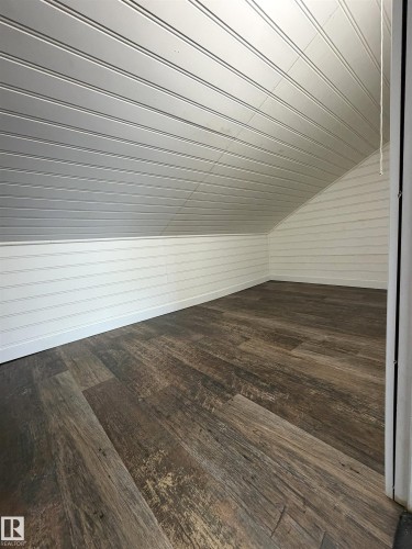 Attic space featuring wood-finish flooring, white beadboard walls, and a sloped beadboard ceiling - 19F Meadowlark Village Nw, Edmonton, AB - Indoor Photo Showing Other Room