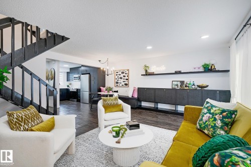 Open-concept living area featuring wood-finish flooring, a contemporary staircase with black railings, and recessed lighting - 19F Meadowlark Village Nw, Edmonton, AB - Indoor Photo Showing Living Room