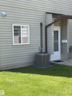 Exterior wall with horizontal siding, featuring a white-framed window and a brown downspout - 
