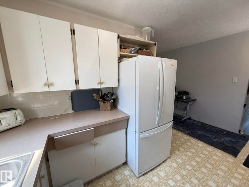 Kitchen featuring white upper and lower cabinetry, a white tile backsplash, and light-toned countertops - 10837 155 Street Nw, Edmonton, AB - Indoor
