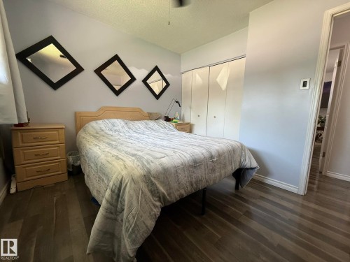 Bedroom featuring wood-finish flooring, light gray walls, a window with curtains, and a bi-fold door closet - 10837 155 Street Nw, Edmonton, AB - Indoor Photo Showing Bedroom