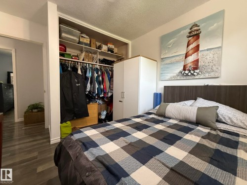 Bedroom featuring a large open closet with built-in shelving, wood-finish flooring, and a dark wood-finish headboard - 10837 155 Street Nw, Edmonton, AB - Indoor Photo Showing Bedroom