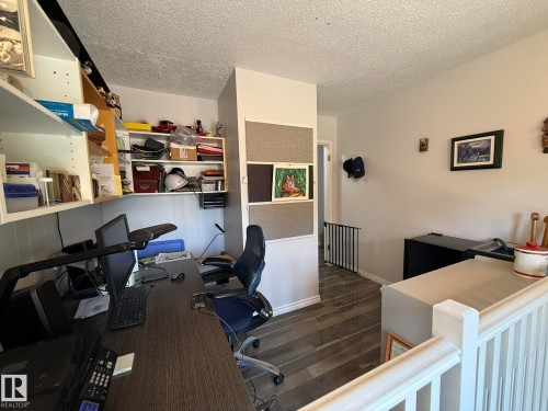 Dedicated workspace featuring built-in shelving, wood-finish flooring, and a white balustrade - 10837 155 Street Nw, Edmonton, AB - Indoor Photo Showing Other Room