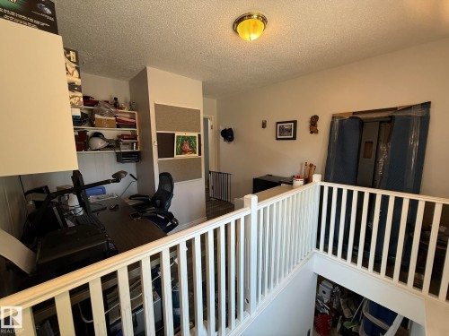 Upper-level landing featuring a white painted railing and a recessed nook with built-in shelving and beadboard paneling - 10837 155 Street Nw, Edmonton, AB - Indoor Photo Showing Bedroom
