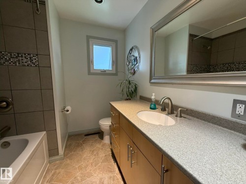 Bathroom featuring a light-toned vanity with an integrated sink, a framed mirror, and a tiled shower/tub combination - 10837 155 Street Nw, Edmonton, AB - Indoor Photo Showing Bathroom
