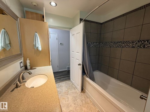 Bathroom featuring a full bathtub with tile surround, mosaic tile accent band, and an integrated shower - 10837 155 Street Nw, Edmonton, AB - Indoor Photo Showing Bathroom