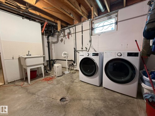 Utility area featuring a laundry sink, exposed wood ceiling joists, and a concrete floor with a floor drain - 10837 155 Street Nw, Edmonton, AB - Indoor Photo Showing Laundry Room