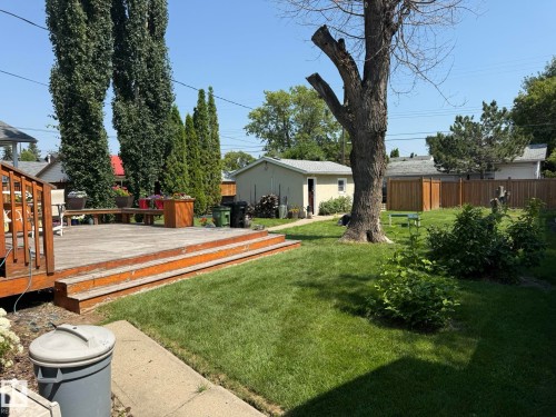 Spacious backyard featuring a large wooden deck with steps, a manicured lawn, established perimeter trees, and a detached garage - 10837 155 Street Nw, Edmonton, AB - Outdoor With Backyard