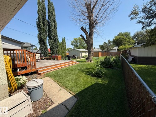 Expansive backyard featuring a multi-level wood deck, a manicured lawn, and mature trees - 10837 155 Street Nw, Edmonton, AB - Outdoor