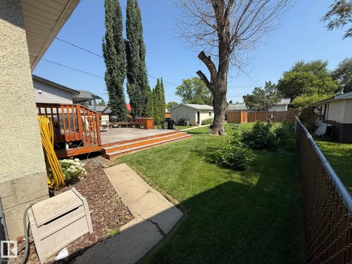 Expansive backyard featuring a multi-level wood deck, a concrete walkway, mature trees, and a manicured lawn - 10837 155 Street Nw, Edmonton, AB - Outdoor