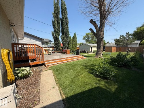Expansive backyard featuring a multi-level wood-finish deck, mature trees, green lawn, and a detached shed - 10837 155 Street Nw, Edmonton, AB - Outdoor With Deck Patio Veranda