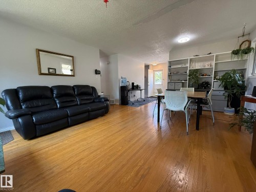 Hardwood flooring extends throughout this open living area, featuring a built-in shelving unit, white walls, and a ceiling light fixture - 10837 155 Street Nw, Edmonton, AB - Indoor Photo Showing Living Room