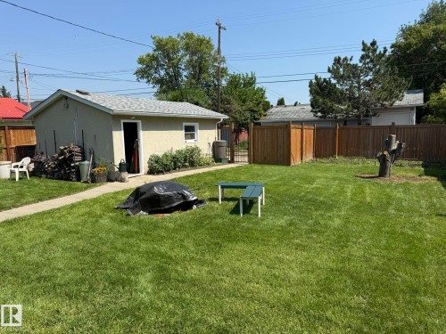 Expansive backyard featuring a manicured lawn, a detached stucco garage with an asphalt shingle roof, a paved walkway, and wood privacy fencing - 10837 155 Street Nw, Edmonton, AB - Outdoor With Backyard