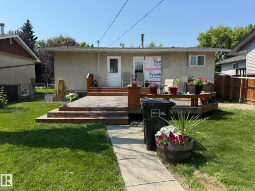 Expansive backyard featuring a multi-level wood-finish deck with integrated planter boxes, a concrete pathway, and a stucco exterior - 10837 155 Street Nw, Edmonton, AB - Outdoor With Deck Patio Veranda
