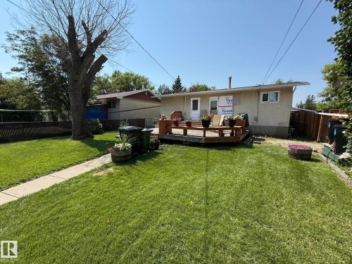 Rear exterior featuring a wood deck, stucco siding, and a spacious lawn - 10837 155 Street Nw, Edmonton, AB - Outdoor With Deck Patio Veranda With Backyard With Exterior