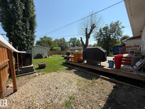 Expansive backyard featuring a large wooden deck, manicured lawn, and a gravel patio area - 10837 155 Street Nw, Edmonton, AB - Outdoor