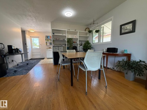 Hardwood flooring extends throughout this interior space, featuring a built-in shelving unit and a white-framed window - 10837 155 Street Nw, Edmonton, AB - Indoor Photo Showing Dining Room