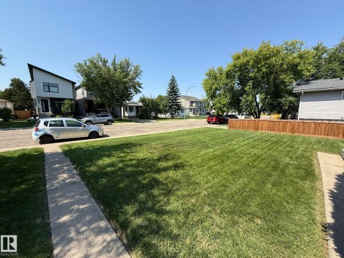Expansive front lawn featuring a newly installed privacy fence - 10837 155 Street Nw, Edmonton, AB - Outdoor