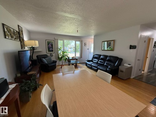 Open concept living and dining area featuring wood-finish flooring, light grey wall paint, and a large front window - 10837 155 Street Nw, Edmonton, AB - Indoor Photo Showing Living Room