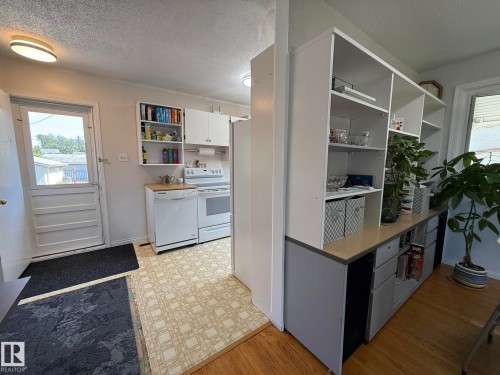 Kitchen area featuring white appliances, patterned vinyl flooring, and a white paneled door with a glass insert - 10837 155 Street Nw, Edmonton, AB - Indoor Photo Showing Kitchen