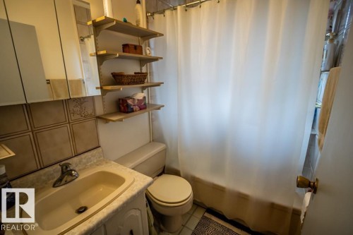 Bathroom featuring a shower-tub combination with a white shower curtain, a toilet, and a vanity with a drop-in sink - 5009 47 Ave, St. Paul Town, AB - Indoor Photo Showing Bathroom