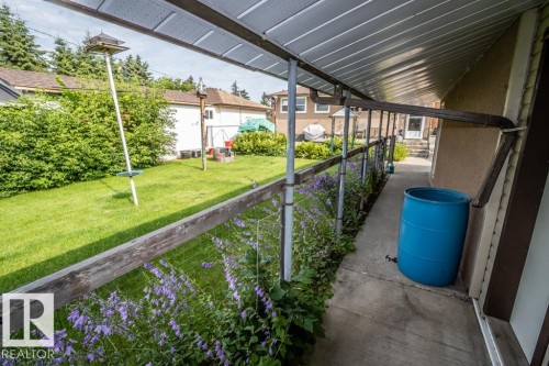 Covered side patio with concrete flooring, bordered by a planted garden bed featuring purple flowering plants - 5009 47 Ave, St. Paul Town, AB - Outdoor