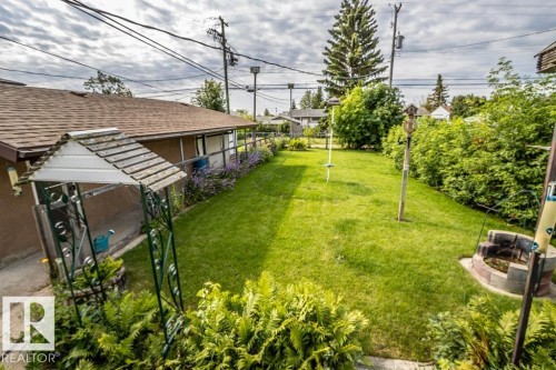 Spacious backyard featuring a manicured lawn, established perimeter greenery, and mature trees - 5009 47 Ave, St. Paul Town, AB - Outdoor