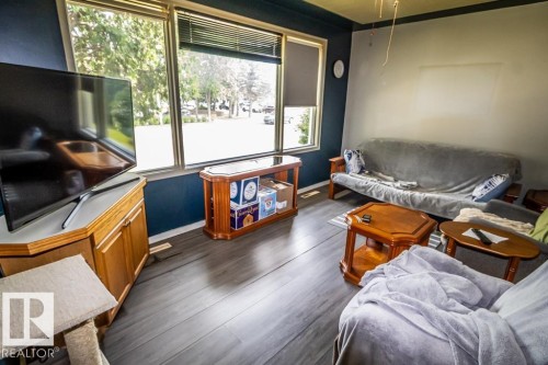 Interior space featuring wood-finish flooring and large windows with blinds - 5009 47 Ave, St. Paul Town, AB - Indoor Photo Showing Living Room