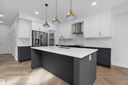 Kitchen featuring a large island with white countertop, stainless steel appliances, herringbone wood-finish flooring, and pendant lighting - 1737 Crossbill Loop Nw, Edmonton, AB - Indoor Photo Showing Kitchen With Upgraded Kitchen