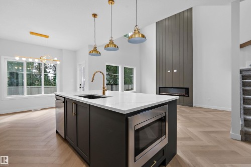 Central kitchen island with a built-in microwave, integrated sink, and gold-finish faucet - 1737 Crossbill Loop Nw, Edmonton, AB - Indoor Photo Showing Kitchen With Upgraded Kitchen