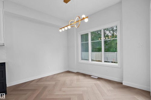 Herringbone wood-finish flooring, white walls, and a modern linear chandelier - 1737 Crossbill Loop Nw, Edmonton, AB - Indoor Photo Showing Other Room
