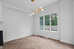 Herringbone wood-finish flooring, white walls, and a modern linear chandelier - 