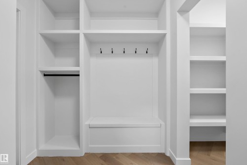 Spacious walk-in closet featuring custom white cabinetry with multiple shelving units, a center island with drawer storage, a clothing rod, and integrated hooks for organized accessory storage - 1737 Crossbill Loop Nw, Edmonton, AB - Indoor With Storage