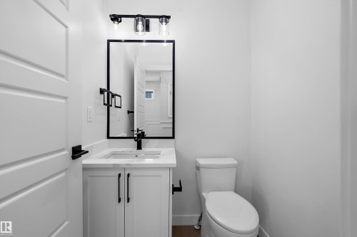 White vanity with a rectangular undermount sink, a stone countertop, and a matte black faucet - 1737 Crossbill Loop Nw, Edmonton, AB - Indoor Photo Showing Bathroom