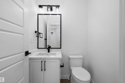 White vanity with a rectangular undermount sink, a stone countertop, and a matte black faucet - 