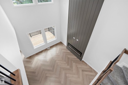 Bright entryway showcasing herringbone wood-finish flooring, dual glass-panel doors with integrated blinds, high ceilings with clerestory windows, and dark gray vertical panel accent wall - 1737 Crossbill Loop Nw, Edmonton, AB - Indoor Photo Showing Other Room